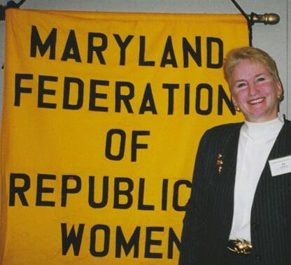 A woman in front of a maryland federation of republican women banner.