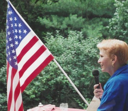 A woman holding a microphone and an american flag.