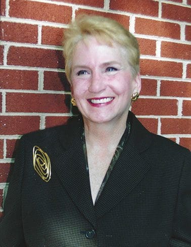 A woman with blonde hair wearing a black suit.